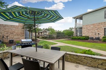 A patio with a table and chairs under a striped umbrella