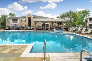 A large swimming pool with a patio and lounge chairs