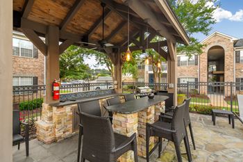 A patio with a table and chairs under a wooden roof