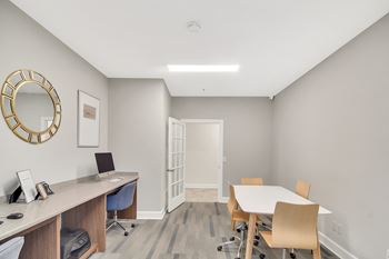 A room with a desk, chairs, and a round mirror on the wall