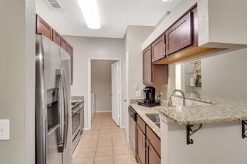 A kitchen with a refrigerator, sink, and cabinets