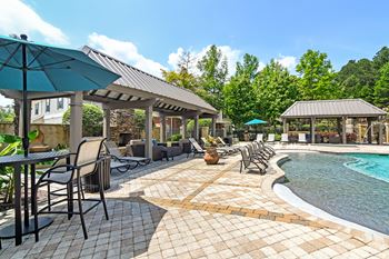 A poolside area with chairs and umbrellas and outdoor fireplace