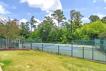 The backyard of a tennis court with a fence and a pond