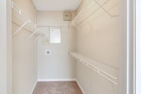 Ridgeland apartment for rent - a spacious walk in closet with white rails and shelves and a white wall at Legacy Apartment Homes in Mississippi 39157
