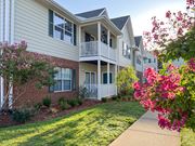 Tyler apartment for rent - an exterior view of an apartment building with a lawn and flowers at The Madison Apartment Homes in Tyler, TX 
