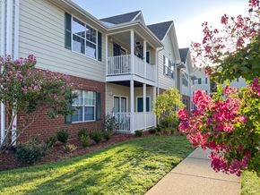 Tyler apartment for rent - an exterior view of an apartment building with a lawn and flowers at The Madison Apartment Homes in Tyler, TX 