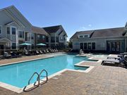 Zachary apartment for rent - A swimming pool surrounded by lounge chairs and umbrellas in front of apartment buildings at Audubon Park Apartment Homes, Zachary, Louisiana