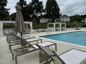 Laurel apartment for rent - a swimming pool with chairs and an umbrella next to it at Laurelwood Apartment Homes, Mississippi, 39440