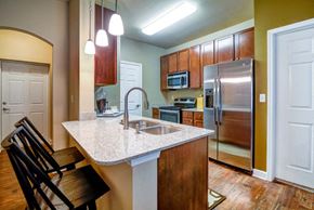Williston apartment for rent - a kitchen with a granite counter top and a stainless steel refrigerator at The Retreat Apartment Homes in North Dakota 58801
