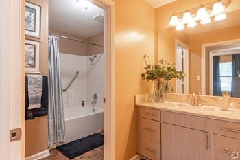 A bathroom with a sink, mirror, and shower 