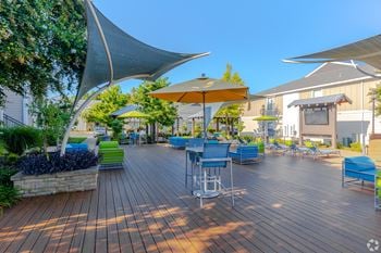 A wooden deck with blue chairs and a yellow umbrella