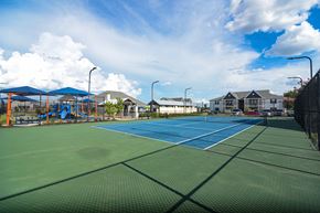 Bossier City apartment for rent - two tennis courts with houses and a playground in the background at Reserve of Bossier City Apartment Homes in Bossier City, Louisiana 71111