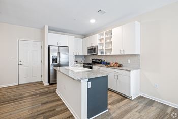 A kitchen with white cabinets and a stainless steel refrigerator 