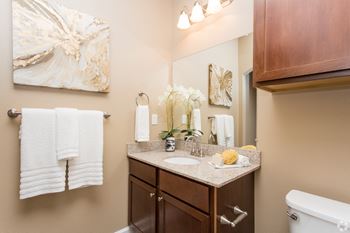 A bathroom with a white tub, brown cabinets, and a painting on the wall