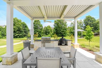A covered patio with a table and chairs and a grill