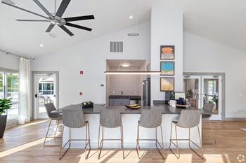 A kitchen with a large island with stools and a ceiling fan
