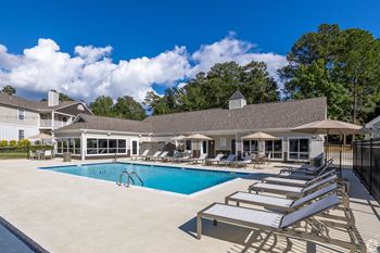 A swimming pool with lounge chairs in front of a building