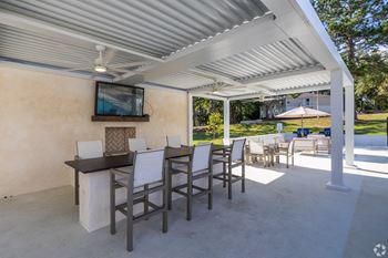 A patio with a bar and chairs and a tv on the wall 