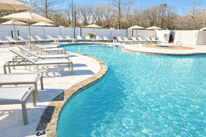 Tyler apartment for rent - A large swimming pool surrounded by sun loungers and umbrellas.