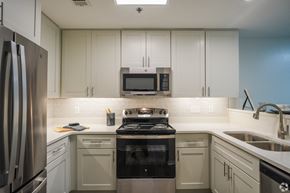 Brandon apartment for rent - a kitchen with white cabinets and a stove and a microwave at The Vineyard at Castlewoods Apartment Homes in Brandon, Mississippi