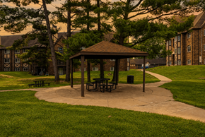 Kalamazoo apartment for rent - A gazebo with picnic tables is surrounded by trees and grass in a park.