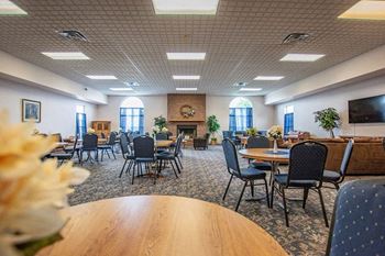 A large room with tables and chairs and a fireplace