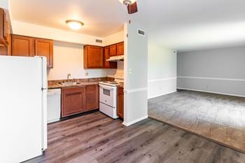 An empty kitchen with wood floors and white appliances