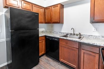 A kitchen with a black refrigerator and wooden cabinets