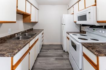 A kitchen with white appliances and granite counter tops