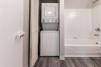 A laundry room with a washer and dryer and a tub in a bathroom