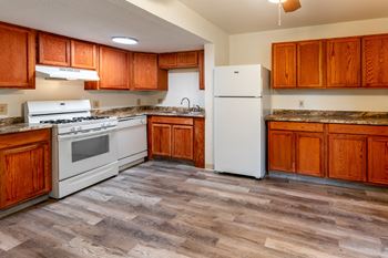 An empty kitchen with white appliances and wooden cabinets