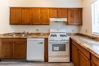 A kitchen with a stove and sink and wooden cabinets