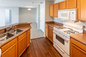 Lowell apartment for rent - a kitchen with wooden cabinets and white appliances and a sink at Creekside at Meadowbrook Apartments, Lowell, 46356
