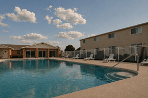 Battle Creek townhouse for rent - A swimming pool surrounded by chairs and buildings.