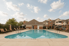 Lowell apartment for rent - A large swimming pool surrounded by lounge chairs and a building in the background.