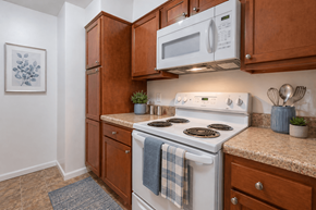 Louisville apartment for rent - A kitchen with a white stove top oven and a white microwave above it.