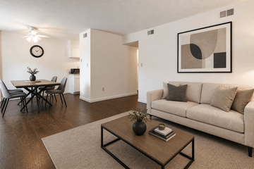 Kalamazoo apartment for rent - A living room with a couch, a dining table, and a painting on the wall.