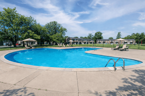 Indianapolis apartment for rent - A large outdoor swimming pool surrounded by trees and a building.