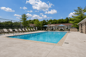 Greenwood apartment for rent - A large outdoor swimming pool surrounded by a fence and lounge chairs.