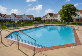 Indianapolis apartment for rent - A large swimming pool surrounded by a metal fence and lounge chairs.