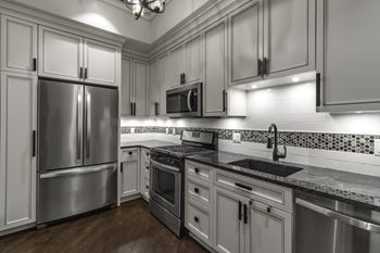 Gray kitchen with stainless appliances and mosaic tile backsplash