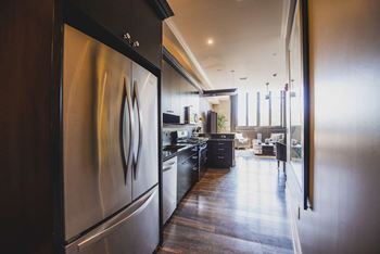 Galley kitchen with stainless steel refrigerator and hardwood floors