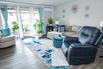 Monroeville apartment for rent - A living room with a blue rug and a black leather sofa.