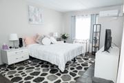 Monroeville apartment for rent - A bedroom with a white bed, a white dresser, and a black and white rug. at Walnut Crossings, Monroeville, PA, 15146