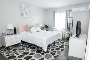 Monroeville apartment for rent - A bedroom with a white bed, a white dresser, and a black and white rug. at Walnut Crossings, Monroeville, PA, 15146