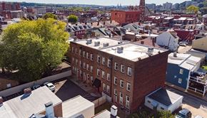 Pittsburgh apartment for rent - a brick building with a white roof and a city in the background