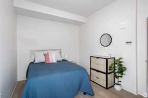 Pittsburgh apartment for rent - A bedroom with a blue bedspread and a white wall.at The Jones Tower at the Collective, Pittsburgh, PA 15203