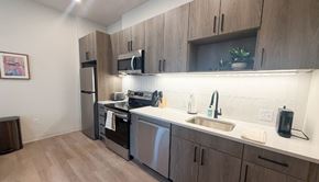 Pittsburgh apartment for rent - A kitchen with wooden cabinets and stainless steel appliances.at The Jones Tower at the Collective, Pittsburgh, PA 15203