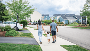 A family of three is walking down a sidewalk