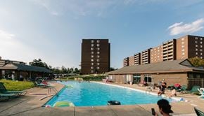 Monroeville apartment for rent - a large swimming pool with people in it and a building in the background  at Walnut Crossings, Monroeville, PA, 15146
